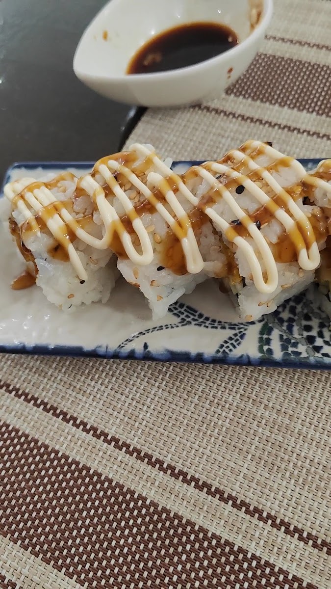 Sushi roll with drizzled sauce on decorative blue and white plate